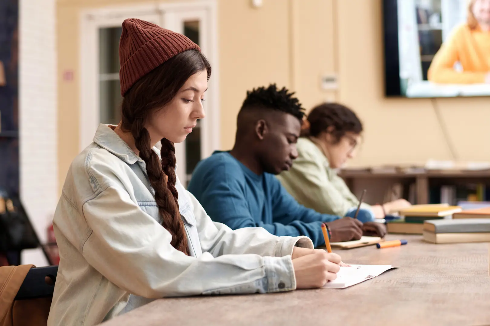 meisje met rode beanie en wist overhemd schrijft toets met potlood